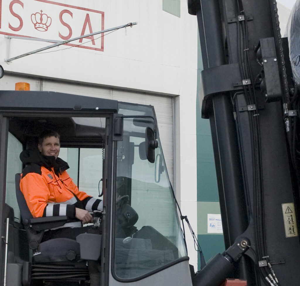 Isojoen Sahan työntekijä istuu ja hymyilee trukissa.